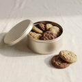 Open keepsake tin of cookies with cookies stacked beside